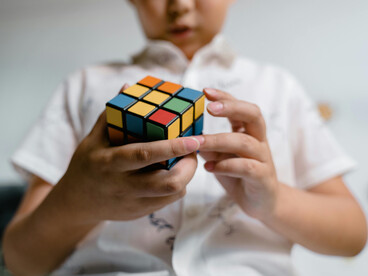 Un enfant résolvant un Rubik's Cube, mettant en lumière l'activation de puissances relationnelles et la coordination des capacités neuronales, corporelles et environnementales dans une tâche cognitive distribuée