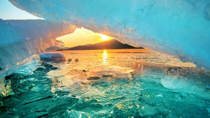 Sunlight shining through thinning glaciers at sunrise, representing the accelerating effects of a warming planet