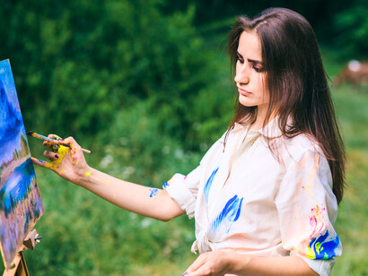 A woman creating art amid nature, symbolising freedom through awareness and expression