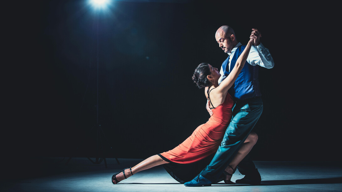 A couple tangoing beneath the spotlight