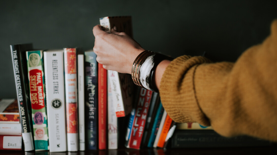 Mujer escoge un libro olvidado en un estante