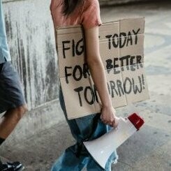 A woman carrying a banner urging to take action now to create a better future