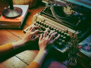 A lady busy writing on her typewriter