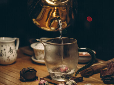 A gold kettle gently pours steaming water into a cup, preparing fresh tea