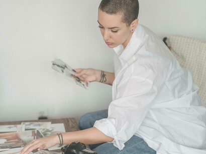 A woman is viewing a spread of photographs and comparing them to the ones she already hoping it will change her viewpoint