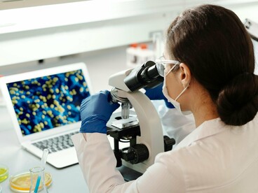 Em laboratório, cientista observa amostras relacionadas à regeneração tecidual. Estudos sobre a polilaminina analisam como o ambiente celular pode influenciar o crescimento e a reconexão neuronal