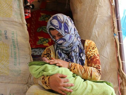 Mujer siria con su bebé en un campo de refugiados