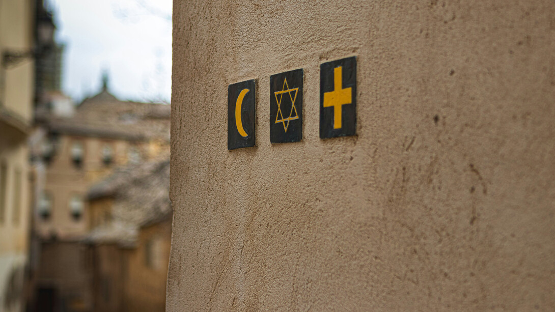 Symbols of Islam, Judaism and Christianity embedded on a wall at a street corner