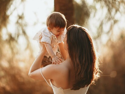 A mother and baby sharing an affectionate embrace outdoors, reflecting the emotional security built through consistent care and connection