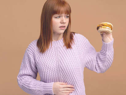 A woman with food intolerance navigating her dietary restrictions while attempting to eat a burger, highlighting the challenges and strategies involved in managing food sensitivities