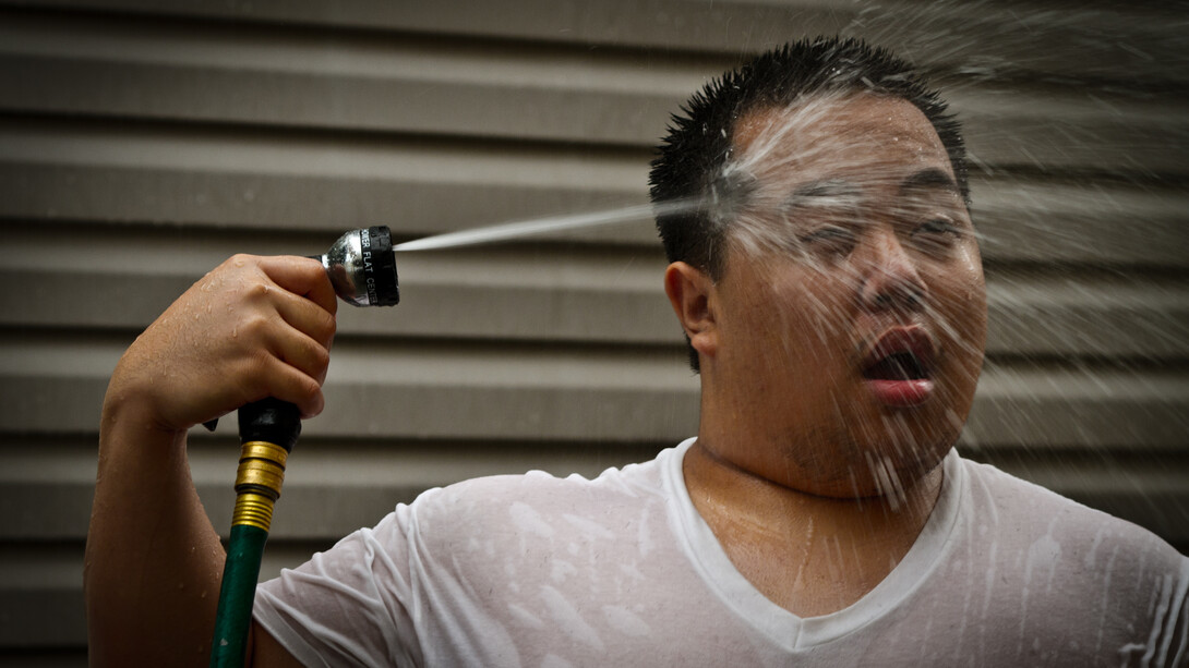 A man cools off with a garden hose shower during the 2011 summer heat wave