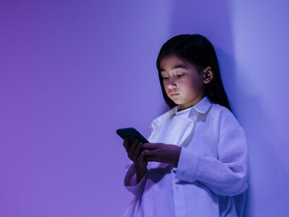 A young girl focused solely on her smartphone, symbolising the immersive pull of smartphones on daily life