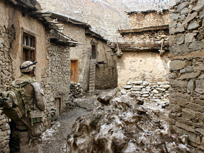 A soldier stands between empty houses in a village Afghanistan 
