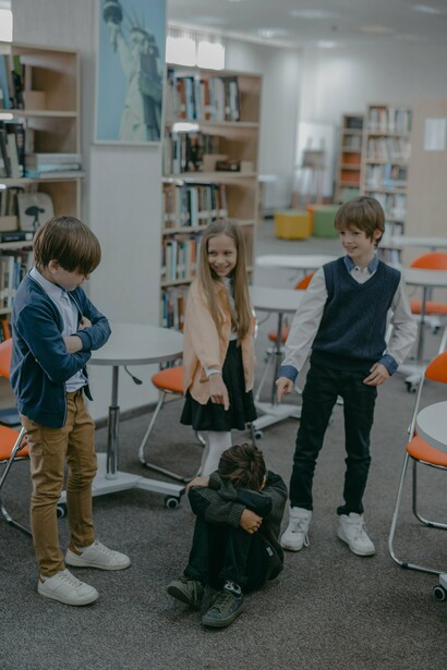 Young boy covers his face as other students laugh at him