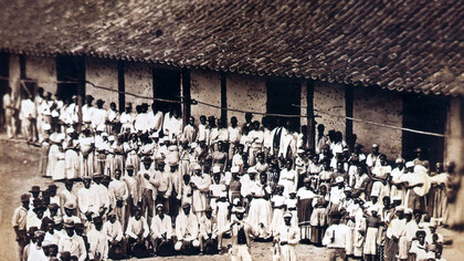O Congado é uma celebração que une religiosidade, música e história, preservando memórias e identidades em um ato de resistência. Foto encontrada no livro "Coleção Princesa Isabel: Fotografia do século XIX", de Bia Corrêa do Lago, em que é possível ver pessoas negras escravizadas celebrando o Congado, em uma fazenda na província de Minas Gerais, Brasil, 1876