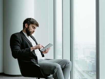A man tapping away on his tablet to manipulate and bolster his self-interest 