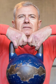 An elderly man lifting a heavy kettlebell, symbolizing longevity, healthspan optimization, and physical resilience