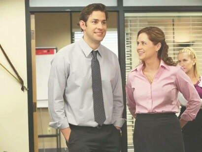 Jim and Pam smiling while delivering news in a scene from "the office"