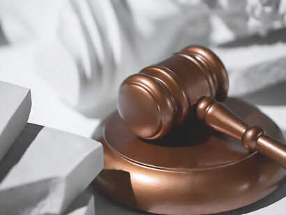 The image of a judge's gavel and fallen statues serves as a poignant visual metaphor