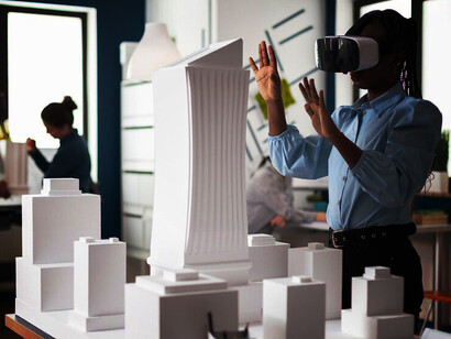 In a modern architectural office, an architect examines a 3D plan through VR goggles, while an engineer with a VR headset works alongside a table featuring a city project model