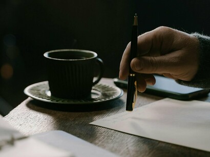 Pessoa escrevendo à mão. Depois de extasiantes e loucas correrias a desaceleração desponta e talvez isso seja importante, mesmo decisivo para refletir e tentar alcançar algum pudor cartesiano, minimamente lógico e consentâneo com os momentos e mementos que vivemos neste planeta assolado por tanta dúvida e incertezas, talvez por demais impróprio para consumo…