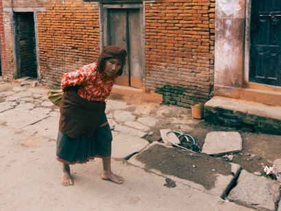 On the margins of society, an elderly woman struggles, emblematic of the failure of cosmetic solutions and the urgent need for profound global reforms to address poverty and environmental degradation