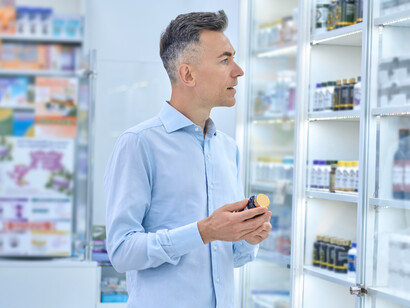 A man selects medicines in a pharmacy as a pharmacist advises him on dietary supplements