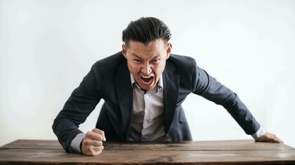 A man not managing his stress levels to the point where he's pounding on the table with anger
