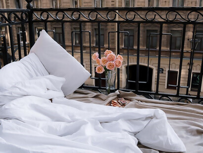 White bed set on the balcony with pink roses next to it