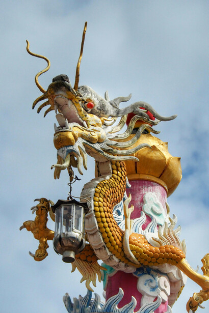 A vibrant Naga-style dragon statue in Thailand is set against a clear blue sky, symbolizing mythological serpent traditions