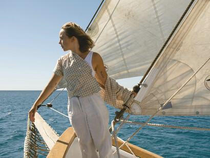 Back view of a woman standing on a boat, sailing through the Adriatic on a luxury travel experience