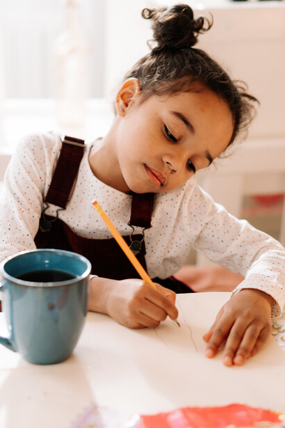 Criança desenha livremente em folha de papel 