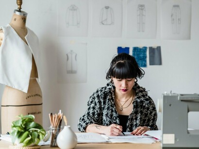 A fashion designer focused on converting an idea into a detailed sketch, reflecting the experience and intuition that technology cannot easily replace