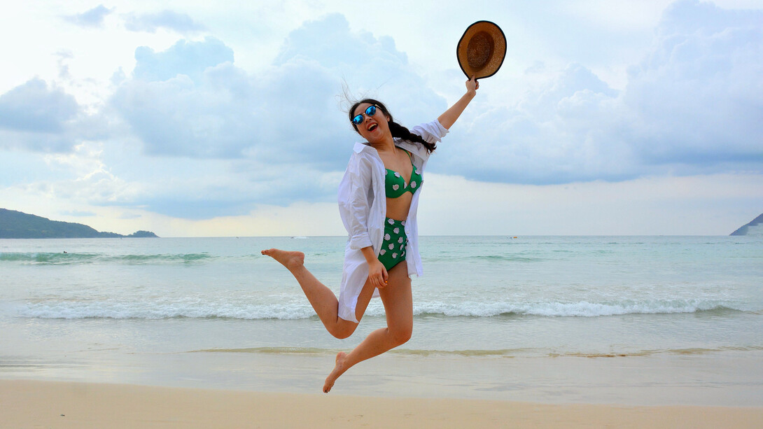 Chica desenfadada salta en la orilla del mar con su 'outfit' playero