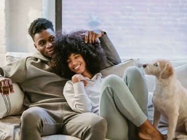 Comfortably seated on a sofa, a young couple shares a joyful moment that reflects love, companionship, and everyday happiness