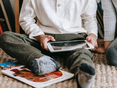 Criança lê o mesmo livro físico em versão digital e animada no tablet