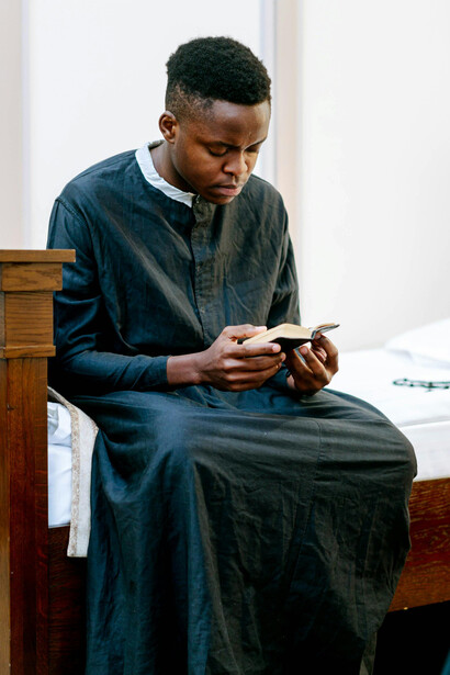A man in black attire holding a Bible as he prays in silence