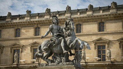 A monumental statue of Louis XIV towering before royal architecture, representing how the execution of a king rarely destroys the structures that sustained his power