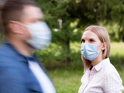 Park scene depicting social distancing during the COVID-19 pandemic: a man and a woman observing health guidelines