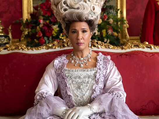 Queen Charlotte from Bridgerton seated in an ornate palace setting, representing the grandeur and unapologetic extravagance of Regency-inspired fashion