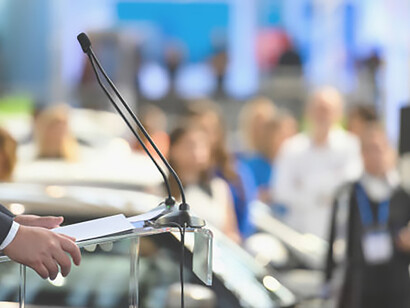 A statesperson eloquently delivers a public address, commanding attention from the lectern
