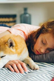 A woman dozing with her dog, capturing the simple, restorative power of pausing in a restless world