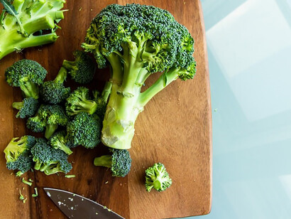 A vibrant stalk of broccoli displayed on a rustic brown wooden chopping board, showcasing a nutrient-packed superfood