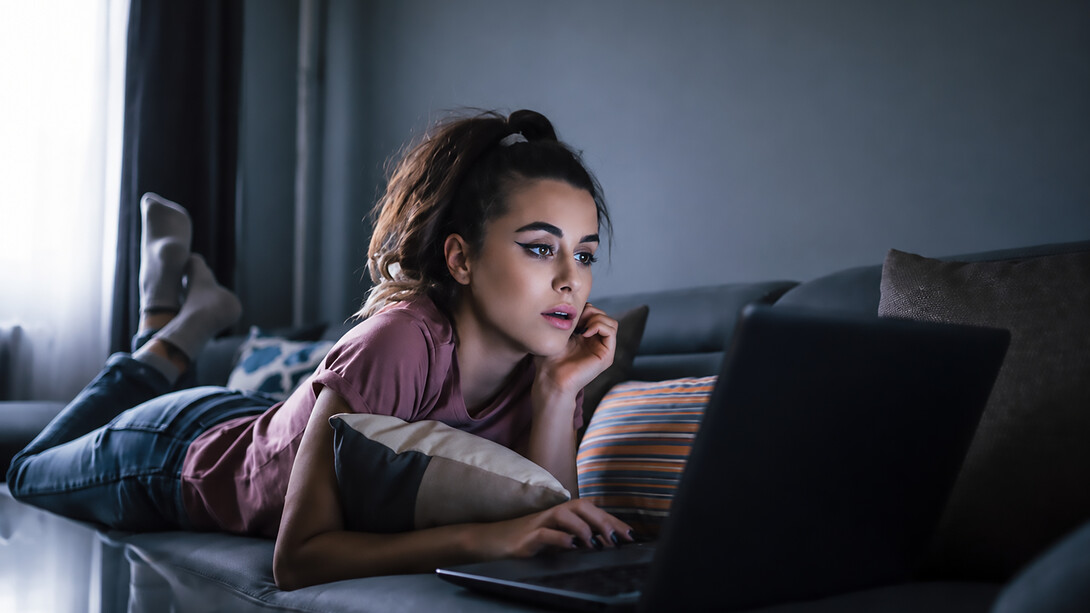 Woman relaxing on the couch while choosing a movie to stream and binge-watch at home