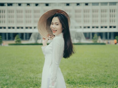 Mujer alegre, en traje tradicional frente al Palacio de la Independencia, Ciudad Ho Chi Minh, Vietnam