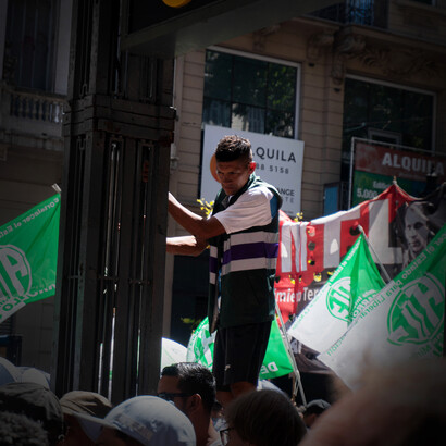 Ciudadano argentino se sujeta a una valla durante la manifestación contra el gobierno de Milei en Buenos Aires, Argentina