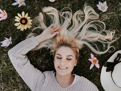 Happy woman relaxing on the grass amongst flowers
