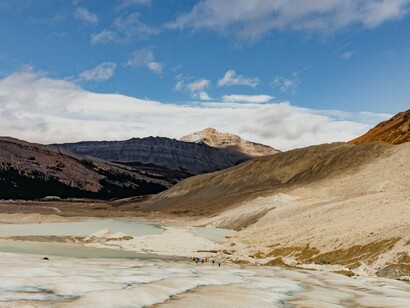People gathered on a snowy slope, with melting glaciers in the background, highlighting the impact of global warming