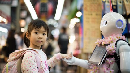 A young girl giving an AI robot the universally understood gesture of a high five
