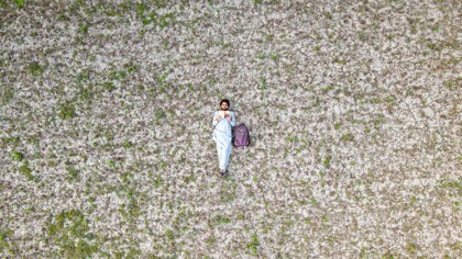Homem se sente em casa ao ler livro em uma ampla grama a céu aberto